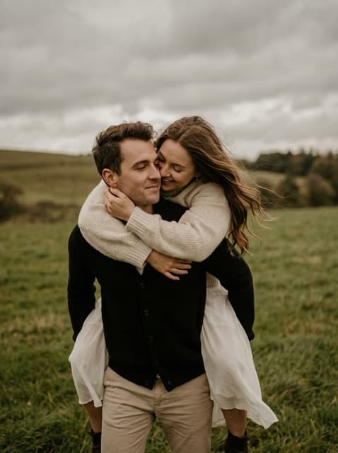 Romantic couple in a windy field, intimate and carefree.